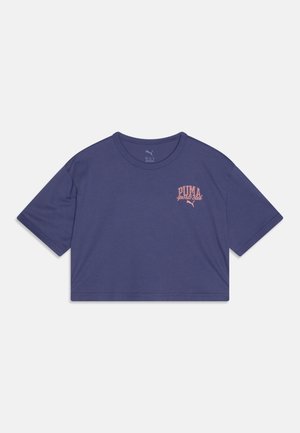 Pusiau nupjautas purpurinis marškinėliai, pagaminti iš medvilnės; turi trumpas rankoves ir apvalų iškirpimą; priekyje yra rožinė "PUMA sporto klubas" teksto logotipas.