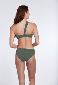 Zelený bikiny set s jedným ramienkom, ktorý predvádza hladký, elastický materiál a minimálne logo na zadnej strane.