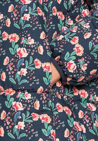 Blomstret dunjakke i navy med mønstre i pink, fersken og grøn. Har quiltet tekstur og sidelommer. Blødt stof.