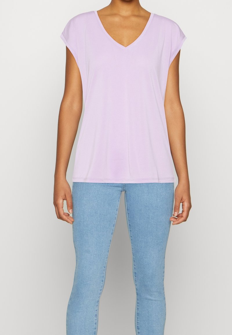 Lila kortärmad V-ringad topp i ett mjukt tyg, tillsammans med ljusblå skinny jeans. Toppen har en avslappnad passform och korta ärmar.