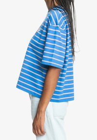 Blå randig kortärmad t-shirt med rosa ränder, korta ärmar och mjuk bomullstextur. Har en avslappnad och ledig passform.