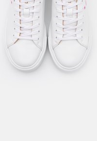 Baskets en cuir blanc à texture lisse, avec des lacets blancs, un logo rose en détail et un design à bout arrondi.