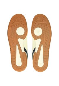 Sneakersulor med en mönstrad gummidesign. Krämfärgad överdel med marinblå accenter, texturerad yta och en distinkt mönstring på sulan.