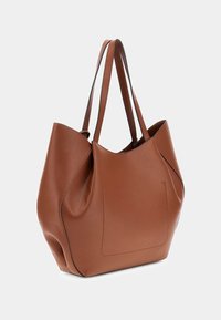 Braune Leder-Tasche mit weicher Struktur, langen Griffen und minimalistischem Design, das dezente Nähte und keine sichtbaren Beschläge aufweist.