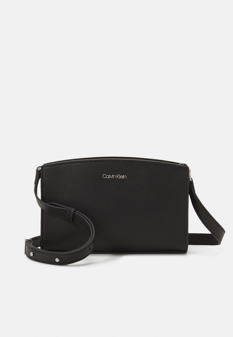Borsa a tracolla in pelle nera con una texture liscia, dotata di chiusura con zip e tracolla regolabile. Piccolo logo argento sul davanti.
