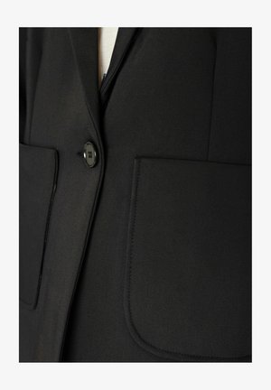 Blazer nero con un bottone lucido, due grandi tasche a toppa e una texture di tessuto liscia con sottili dettagli di sartoria.