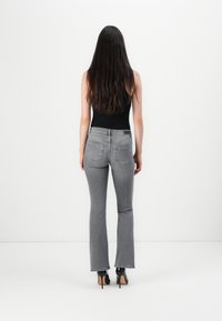 Grå blyantsjeans med en tettsittende silhuett, to baklommer og et lite merkelapp på linningen; glatt denimtekstur.