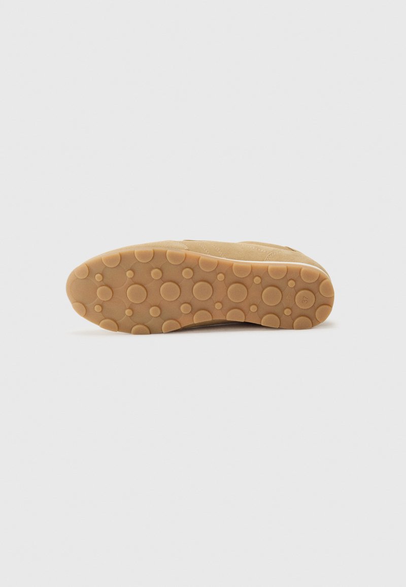 Beżowe obuwie z teksturowanej zamszowej cholewki, z elastyczną gumową podeszwą z zaokrąglonymi, wystającymi punktami dla lepszej przyczepności i komfortu.
