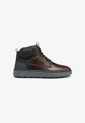 Bottes montantes en cuir brun avec un col rembourré noir, une semelle en caoutchouc gris, six œillets et des accents texturés. Design léger et durable.