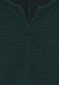 Tissu texturé vert foncé avec un motif de vagues subtil, doté d'un décolleté en V et de détails de couture centrale. Conçu pour une silhouette ajustée.