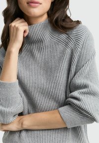 Gray ribbed knit sweater with a high collar and rolled sleeves, featuring a soft, textured appearance and relaxed fit.