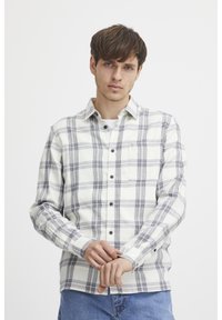 Long-sleeve plaid shirt in white and navy with button-up closure, chest pocket, and a relaxed fit. Cotton blend fabric with a soft texture.