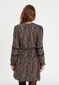Black floral dress with a gathered waist, long sleeves, and a textured fabric featuring multicolored floral patterns.