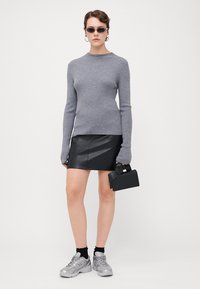 Grå ribbestrikket genser, svart skinn mini skjørt, svart håndveske, sølv sneakers og solbriller. Enkel design, tettsittende silhuett, teksturert stoff.