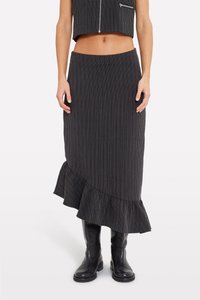 Fustă midi cu dungi negre, având o margine volanată, realizată dintr-un material texturat. Asortată cu cizme negre până la genunchi pentru un look complet.