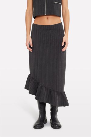 Falda midi a rayas negras con dobladillo rizado, confeccionada en tejido texturizado. Combinada con botas negras hasta la rodilla para un look completo.