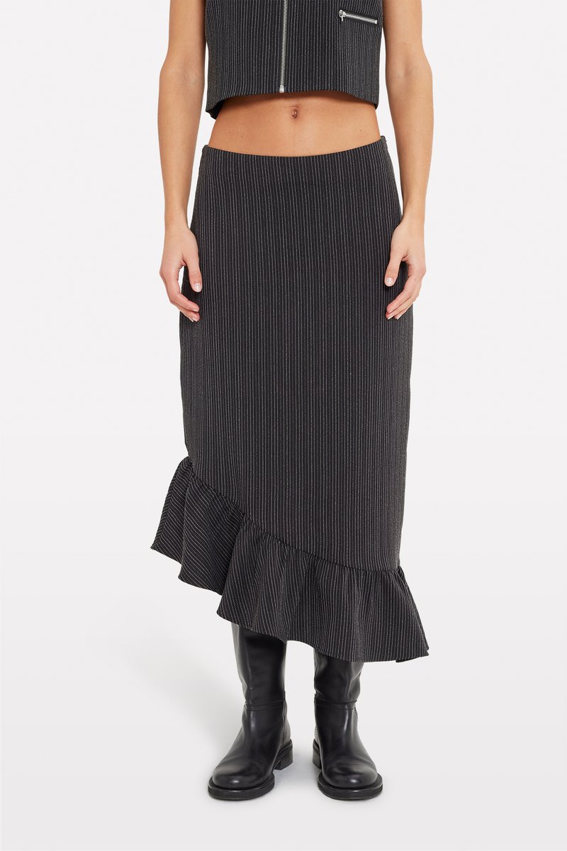 Fustă midi cu dungi negre, având o margine volanată, realizată dintr-un material texturat. Asortată cu cizme negre până la genunchi pentru un look complet.