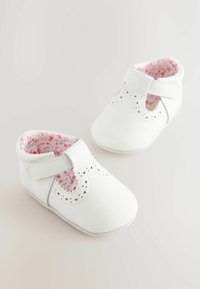 Bébés chaussures blanches en cuir synthétique lisse, dotées de motifs découpés au laser, d'une sangle à scratch et d'une doublure à imprimé floral.