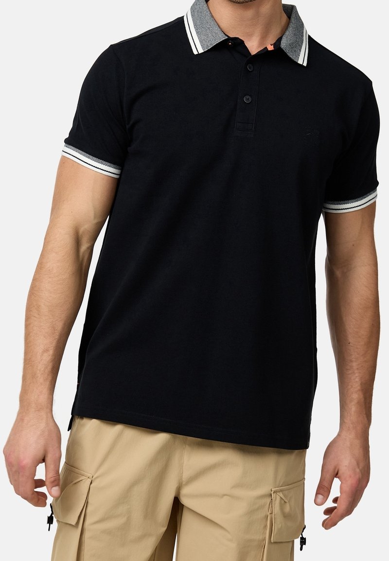 Schwarzes Poloshirt mit grauem gestreiften Kragen, Drei-Knopf-Leiste und gerippten Bündchen; glattes Material; dezentes Logo auf der Brust.