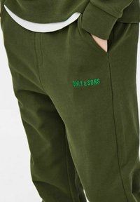 Zielone bawełniane spodnie dresowe o luźnym kroju, z bocznymi kieszeniami i haftowanym logo „ONLY & SONS” w kontrastowym zielonym kolorze.