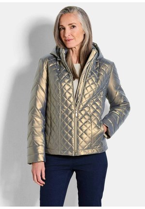 Gequilte metallic grijze jas met een capuchon, voorzien van diagonale stiksels, een rits aan de voorkant en zijzakken. Gekomd met een lichte trui en donkere spijkerbroek.
