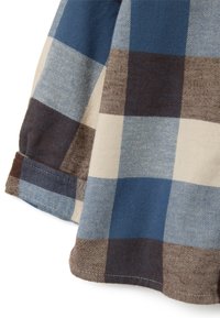 Camisa de franela a cuadros con grandes cuadros azules, beige y marrones. Tela suave con puños doblados y detalles de costura visibles.