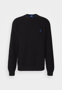 Pull en maille noire avec texture côtelée, col rond et manches longues. Présente un emblème bleu sur la poitrine et est fabriqué dans un tissu doux.