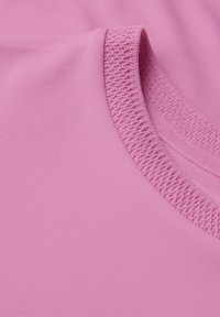 Maglietta sportiva rosa chiaro con colletto rotondo e dettagli in rilievo, realizzata in tessuto liscio ed elastico per garantire comfort.