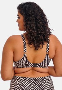 Mustekki mustavalkoraidallinen bikiniyläosa, jossa on säädettävät hihnat ja klipsisuljenta. Korostaa rohkeaa geometrista kuviota ja pehmeää tekstuuria.