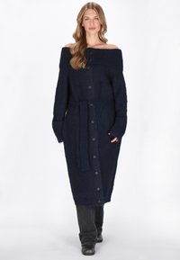 Tengerészkék, vállnélküli kötött ruha hosszú ujjal, gombos elülső résszel és megkötős övvel. Texturált szövet és bordázott nyak, teljes hosszúságú sziluett.
