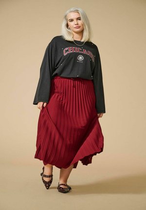 Black long-sleeve shirt with "Chicago" graphic, paired with a pleated burgundy skirt. Black spiked flats complete the outfit.
