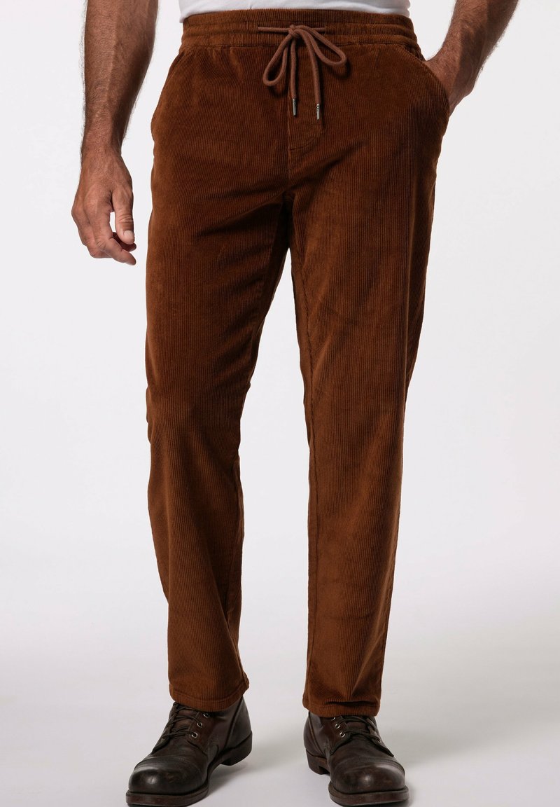 Pantalones de pana marrones con un diseño de pierna recta, cinturilla ajustable con cordón y dos bolsillos laterales, llevados con botas negras.