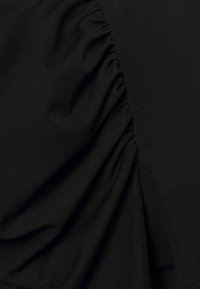 Schwarzer Stoff mit geraffter Textur, der weiche Drapierungen und eine glatte Oberfläche aufweist. Das Design beinhaltet subtile Falten für zusätzliche Dimensionen.