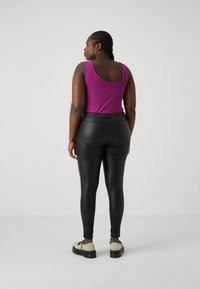 Purple tank top with a scoop back, paired with black faux leather leggings. Chunky cream shoes with dark soles complete the outfit.