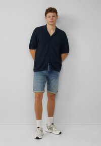 Marine gestreepte short-sleeve shirt, lichtblauwe denim shorts, witte sokken en grijze sportschoenen. Eenvoudig ontwerp, relaxte pasvorm en opgerolde mouwen.
