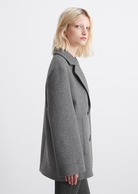 Cappotto grigio in misto lana con collo a rever, chiusura doppio petto, tasche laterali e vestibilità rilassata, caratterizzato da una texture morbida e linee pulite.