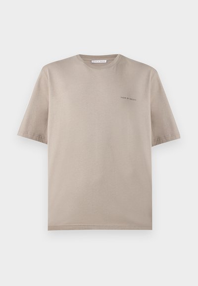 Μπεζ κοντομάνικο μπλουζάκι με στρογγυλή λαιμόκοψη και μικρό λογότυπο «Tiger of Sweden» στο αριστερό μέρος του στήθους, απεικονίζεται σε λευκό φόντο.