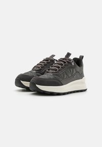 Zapatillas de deporte gris oscuro hechas de tela acolchada y ante, con una gruesa entresuela blanca, cordones redondos y suela de goma texturizada para un mejor agarre.