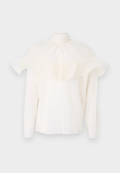 Λευκή μπλούζα με ψηλό γιακά, υφασμάτινη υφή και υπερμεγέθη φουσκωτά μανίκια. Μακριά μανίκια με εφαρμοστούς καρπούς, χαλαρή εφαρμογή σε όλη την επιφάνεια.