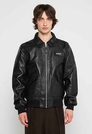 Schwarze Lederbomberjacke mit Reißverschluss, spitzem Kragen und zwei vorderen Taschen; mit gerippten bündchen und Saum, Logopatch auf der Brust.