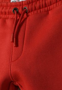 Rode katoenen joggers met een elastische tailleband, voorzien van een trekkoord en zijzak. Gladde textuur met zichtbare stikdetails.