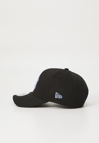 Boné ajustado preto com aba curva, apresentando um logo bordado azul claro na frente e um pequeno emblema na lateral.