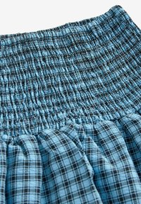 Tessuto a quadri blu e nero, vita elasticizzata, dettaglio di smock testurizzato, gonna leggera e ariosa con elementi di design arricciati.