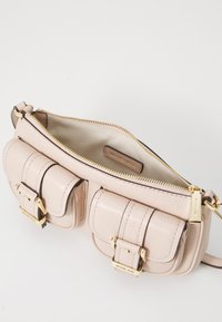 Light pink leather handbag with a textured finish, gold hardware, two front pockets, and a zip closure. Interior is lined in beige fabric.