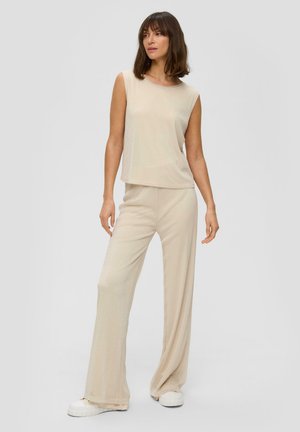 Beige sleeveless top and matching wide-leg pants in a soft, textured fabric. Loose fit with a smooth surface. White sneakers visible.