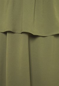 Tessuto a strati verde oliva con una texture liscia e un leggero splendore. Presenta un design drappeggiato con un bordo arricciato sullo strato superiore.