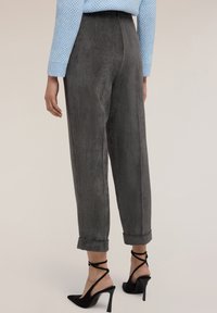 Grijze corduroy broek met een losse pasvorm, met een hoge taille en opgerolde manchetten. Draag een paar zwarte puntige hakken.