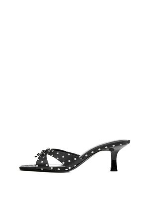 Sandale mule noire à bout ouvert avec des pois blancs, talon bas courbé et un petit nœud sur les brides croisées.