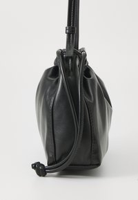 Borsa in pelle nera con una forma morbida e arrotondata. Presenta una chiusura con coulisse e una tracolla sottile e regolabile. Texture liscia con dettagli sottili.