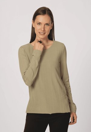 Top de manga larga y ligero en un verde oliva apagado, con textura acanalada y cuello redondo, combinado con pantalones negros ajustados.